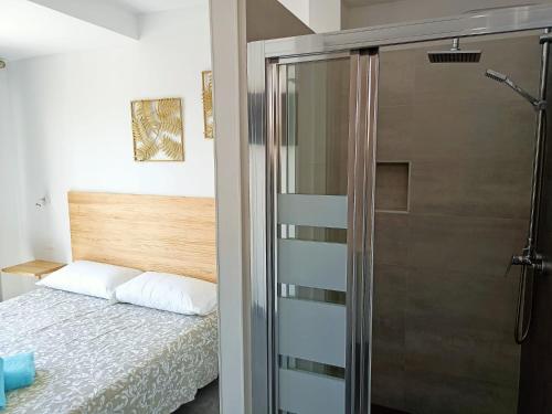 a bedroom with a bed and a glass shower at Complejo Sun's Gardens - Maspalomas in Maspalomas