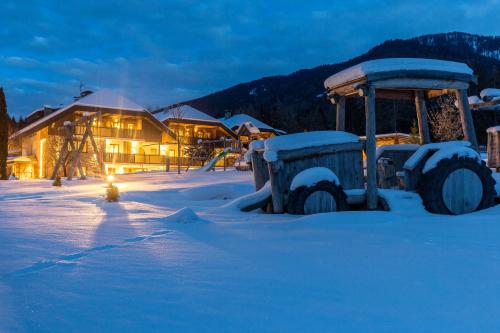 a snow covered field with a tractor in front of a building at Aparthotel Familiaris - Family Apartments - Pools & Spa in Dolomites in Valdaora
