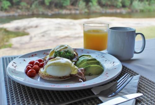 a plate of breakfast food and a glass of orange juice at Lions Rock Rapids - Luxury Tented Camp in Hazyview