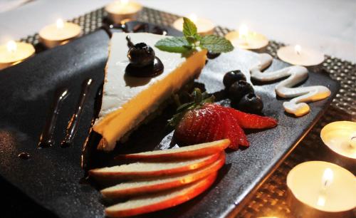 a black plate with a cheesecake and strawberries on it at Lions Rock Rapids - Luxury Tented Camp in Hazyview