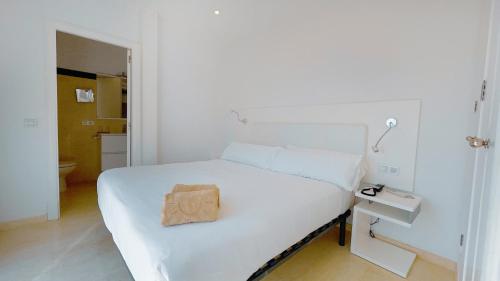 Un dormitorio blanco con una cama blanca con una bolsa marrón. en Lago Resort Menorca - Villas & Bungalows del Lago en Cala'n Bosch