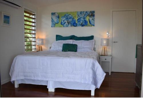 Un dormitorio con una cama blanca y una pintura en la pared en Island Breeze Fiji en Savusavu