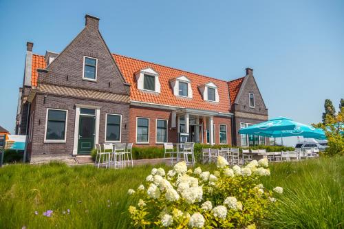 a house with chairs and umbrellas in front of it at EuroParcs Poort van Amsterdam in Uitdam