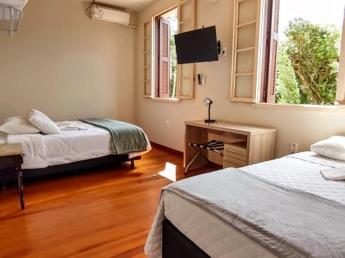 a bedroom with two beds and a flat screen tv at Vila Betânia in Porto Alegre