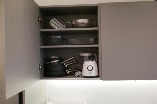 a kitchen cupboard with a blender and pots and pans at Luxurious Short Stay Flat in Milton Keynes in Milton Keynes