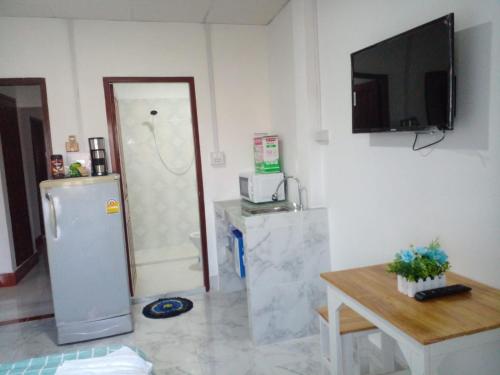 a kitchen with a refrigerator and a table and a tv at Ban Saylomleng Residence in Vientiane