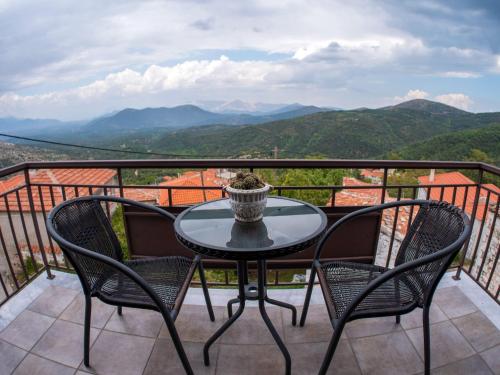 a table and chairs on a balcony with mountains at Erasmion in Áno Dholianá
