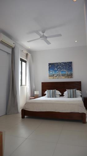 a bedroom with a bed and a ceiling fan at Sunset Beachfront Penthouse Cap Ouest Flic en Flac in Flic-en-Flac