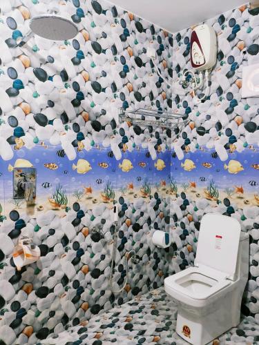 a bathroom with a toilet and a wall covered in balls at Achayans Homestay Mararikulam in Mararikulam