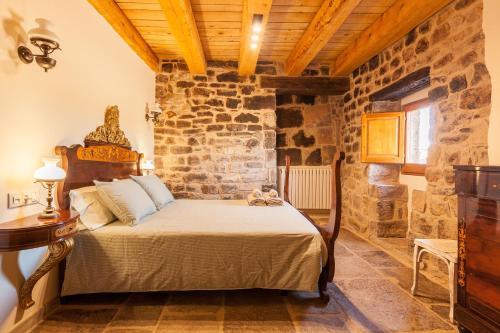 een slaapkamer met een bed en een stenen muur bij Masia Can Pla in San Mateo de Bages