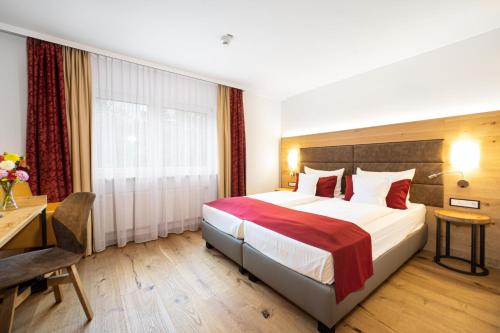 ein Hotelzimmer mit einem großen Bett und einem Schreibtisch in der Unterkunft Park Hotel Laim in München