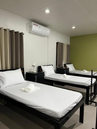 a hospital room with three beds and a fan at Happy Camper Hostel in Coron