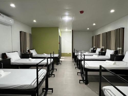 eine Reihe von Betten in einem Zimmer mit Tischen und Stühlen in der Unterkunft Happy Camper Hostel in Coron