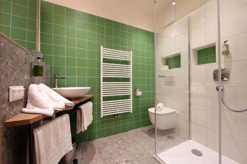 Baño de azulejos verdes con lavabo y aseo en Landgasthof Erber en Zelking