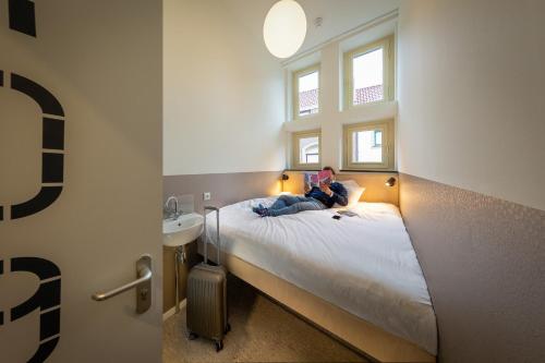 een persoon op een bed in een kleine kamer bij Stadsherberg Ald Weishoès in Venlo