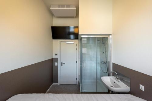 een badkamer met een wastafel en een douche bij Stadsherberg Ald Weishoès in Venlo