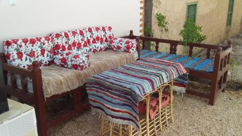 a wooden couch with pillows and a blanket at tayson House in ‘Ezbet Abu Ḥabashi
