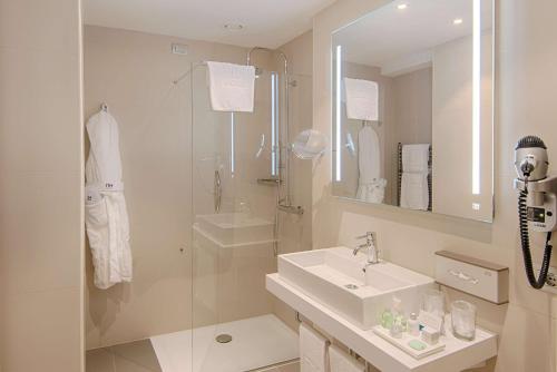 a white bathroom with a sink and a shower at NH Torino Centro in Turin