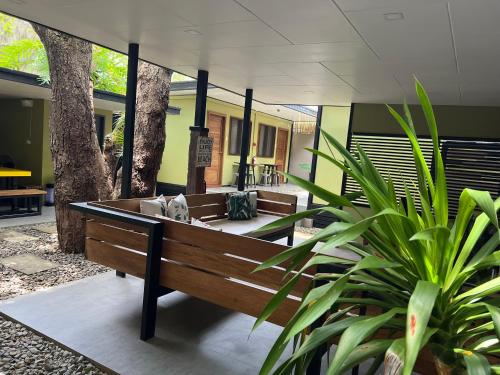 a wooden bench sitting in a courtyard with trees at Happy Camper Hostel in Coron