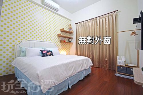 a bedroom with a white bed with yellow polka dots at Dibao 16 Homestay in Fangliao