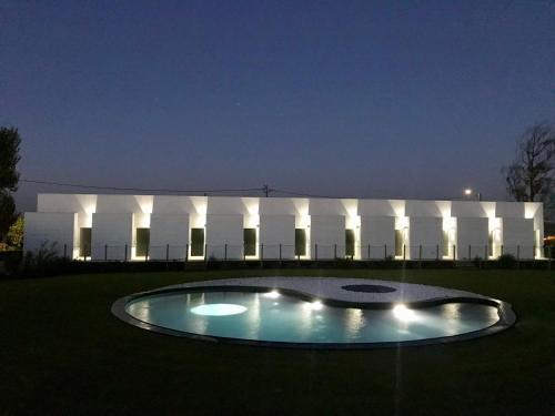 - un bâtiment avec une piscine en face de lui la nuit dans l'établissement Tijosa Eco-House Camp, à Ovar