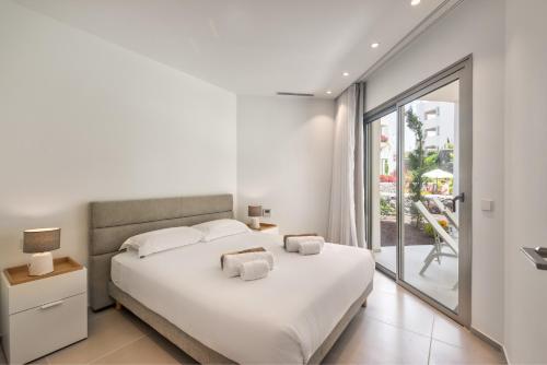 a white bedroom with a large bed and a balcony at Jardines - Adama 01 VISTA PISCINA & JARDIN 2B in Palm-mar