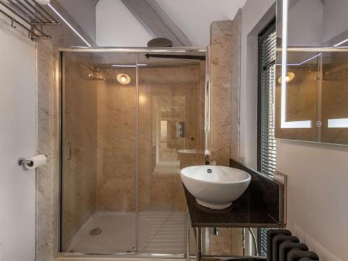 a bathroom with a glass shower and a sink at dairy cottages in Wimborne Minster