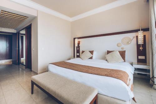 a hotel room with a large bed and a bench at Iberostar Selection Royal El Mansour in Mahdia