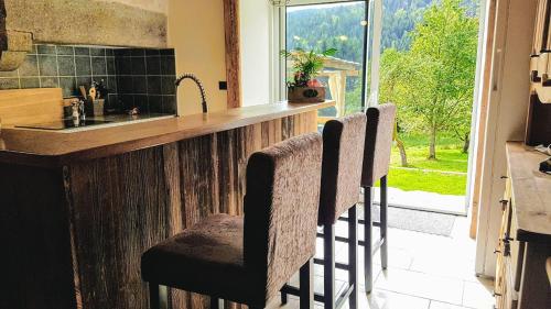 a kitchen with a counter with two bar stools at Joli chalet 12 personnes 200m2 sauna baby-foot in Cleurie