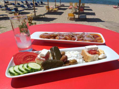 zwei Tabletts Essen auf einem roten Tisch am Strand in der Unterkunft Agali Hotel in Limenaria