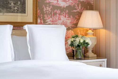 a bedroom with a bed and a lamp and a vase of flowers at Four Seasons Hotel des Bergues Geneva in Geneva