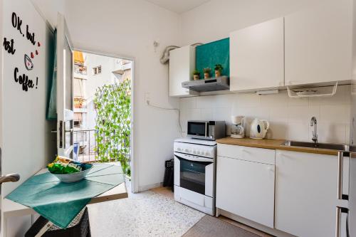 a small kitchen with white cabinets and a table at Mets in Athens