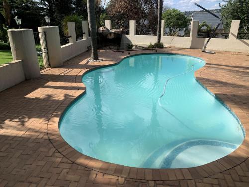 a large blue swimming pool on a brick patio at Safari Apartments -Beautiful 3 bedrooms, 10-seater dining , TV room, Garden & Pool in Johannesburg