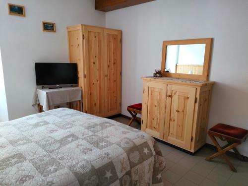 ein Schlafzimmer mit einem Bett und einem TV in der Unterkunft Camere vecchio borgo in Bormio