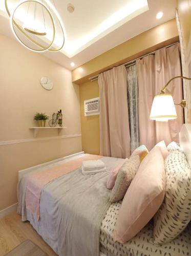 a bedroom with a bed with pillows and a lamp at SMDC Trees Residences Tower 1 - 2BR Newly Renovated Staycation in Manila