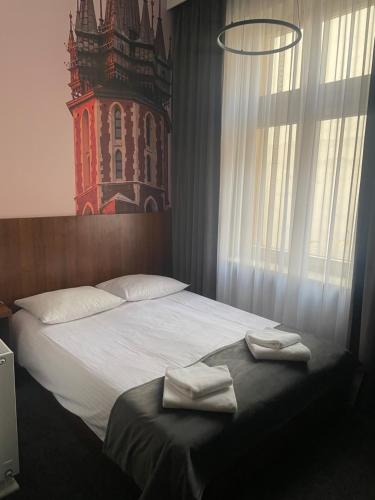 a bedroom with a bed with two towels on it at Hotel Downtown Kraków in Kraków