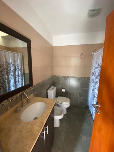 un bagno con lavandino, WC e specchio di Luis II a Villa María