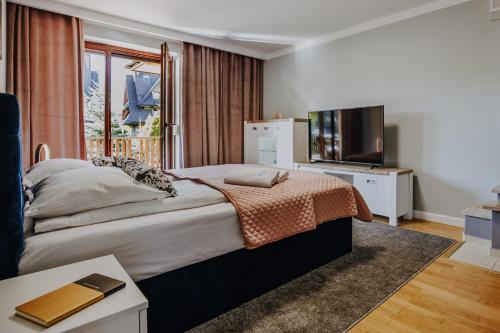 sypialnia z dużym łóżkiem i telewizorem w obiekcie VisitZakopane - Szarotka Apartment w Zakopanem