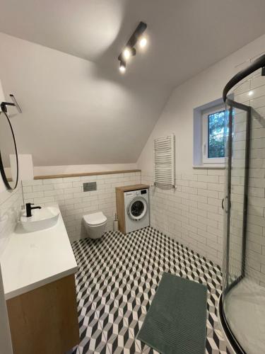 a bathroom with a shower and a washing machine at Leśnisko in Jerutki