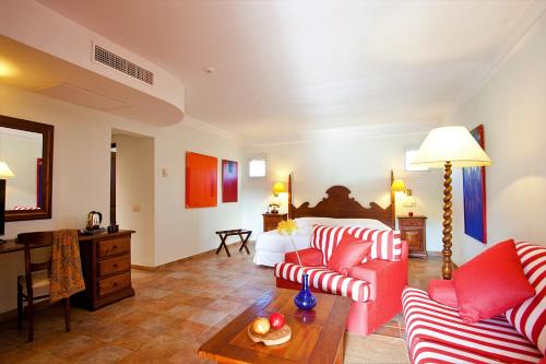a living room with red and white furniture and a bed at Hotel Cala Sant Vicenç - Adults Only in Cala de Sant Vicent