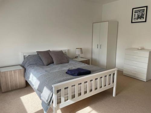 1 dormitorio con 1 cama blanca y armario blanco en Lovely 2-bed flat with well equipped kitchen en Ealing