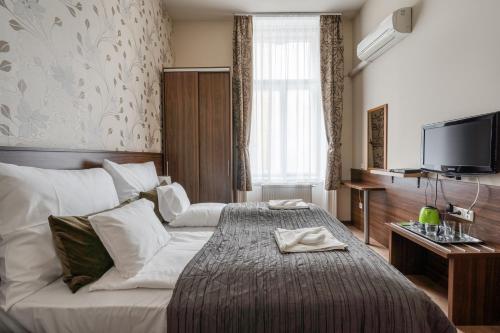 a hotel room with a bed and a flat screen tv at Elit Boutique Rooms- Best Location by BQA in Budapest