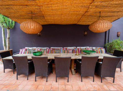 una mesa de madera con sillas y 2 lámparas de araña en Riad Timila, en Marrakech