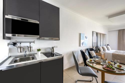 a kitchen with a sink and a table with chairs at Plaza Regency Hotels in Sliema