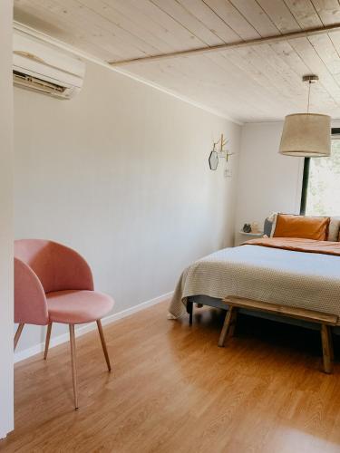 a bedroom with a bed and a chair at Luxurious red cottage with wood stove near lake in Nye