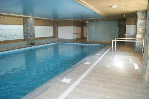 une grande piscine avec de l'eau bleue dans un immeuble dans l'établissement Chalet des Oursons, à Cohennoz