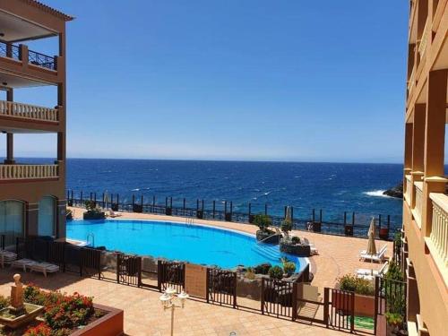 a swimming pool with the ocean in the background at El Nautico Apartment in San Miguel de Abona