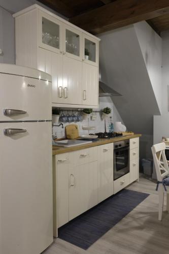 una cucina con armadietti bianchi e frigorifero di Loft Penelope a Tivoli