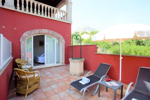 a patio with chairs and a table and an umbrella at Hotel Cala Sant Vicenç - Adults Only in Cala de Sant Vicent