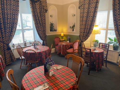 a restaurant with two tables and chairs with red checked tables at Cornerways Guest House in Carlisle